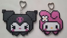 two pixelated animal key chains are shown on a white surface, one is pink and the other is black