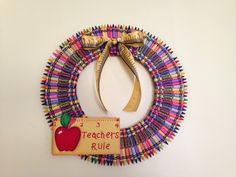 a teacher's wreath made out of crayons with a measuring tape and an apple on it