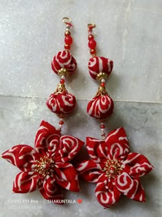 red and white flower earrings with gold accents on marble floor next to each other,