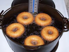 four donuts are being cooked in oil on the stove top with a thermometer