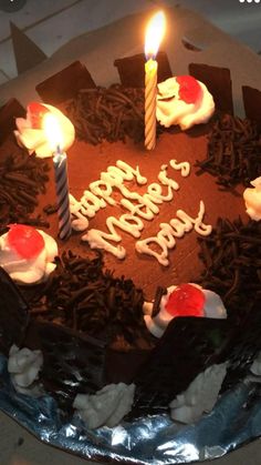 a chocolate birthday cake with lit candles on the top and frosting in the middle