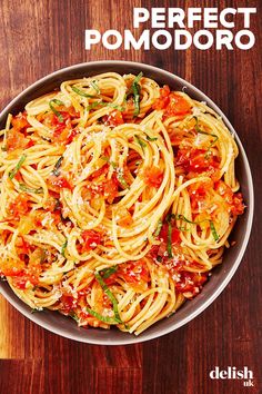 a bowl filled with pasta and sauce on top of a wooden table