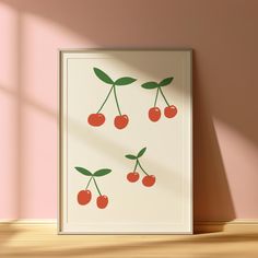 an art print with cherries hanging on a pink wall next to a wooden floor