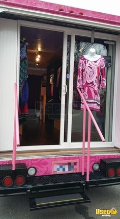 a pink truck is parked in front of a store with its doors open and clothes on display