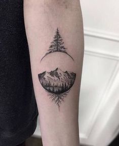 a person with a tattoo on their arm that has trees and mountains in the background