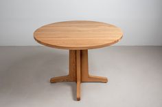 a round wooden table sitting on top of a white floor