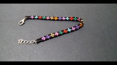 a multicolored beaded bracelet with metal clasps on a gray surface,