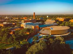 an aerial view of a campus with trees and buildings in the foreground, at sunset