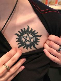 a woman holding her chest with a pentagramil tattoo on it's chest