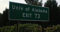 a green street sign sitting in front of some bushes and trees with the words university of alabama exit 73 on it