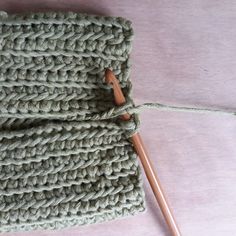 a crocheted green cloth with two knitting needles