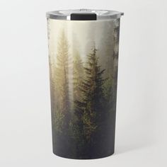 a travel mug with an image of trees in the woods on it's side