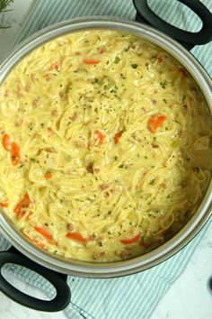 a pot filled with noodles and carrots on top of a table