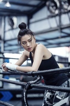 a woman leaning on a rail in a gym