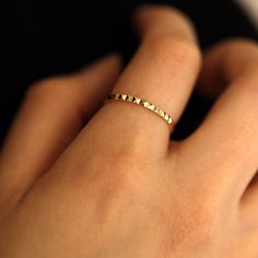 a woman's hand with a gold ring on top of her finger and an arrow shaped band