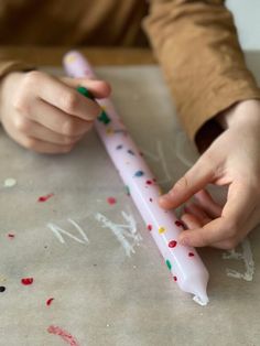 a child is holding a pink toothbrush with sprinkles on the surface