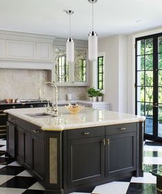 a kitchen with black and white checkered flooring, marble counter tops and an island