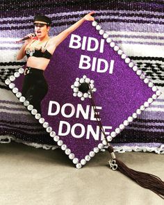 a woman in black and purple outfit holding a microphone on top of a pillow that says, bid bid don't done