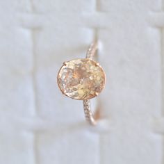 an engagement ring with a yellow diamond in the center on a white brick wall background