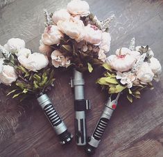 three microphones with flowers in them sitting on a wooden floor next to each other