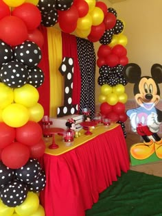 a mickey mouse themed birthday party with balloons and streamers on the wall, table