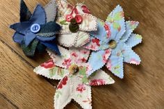 three fabric flowers with buttons on them sitting on a wooden table next to a button