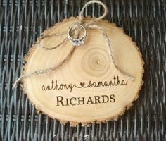 a wooden slice with the words anthony & amanaha on it and two wedding rings tied to each other