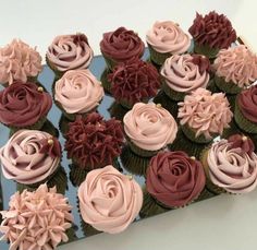 cupcakes decorated with pink and brown frosting on a blue platter in front of a white wall