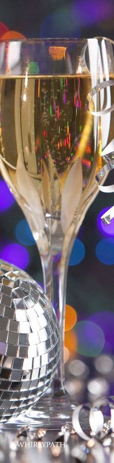 a close up of a wine glass on a table with disco lights in the background