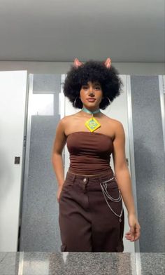 a woman with an afro and cat ears on her head standing in front of a mirror