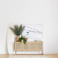 a white surfboard sitting on top of a wooden shelf next to a potted plant