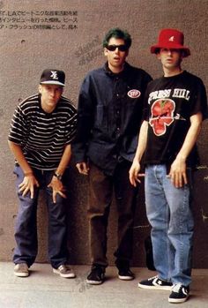 three men standing next to each other in front of a wall