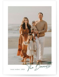 the family is posing for a photo on the beach