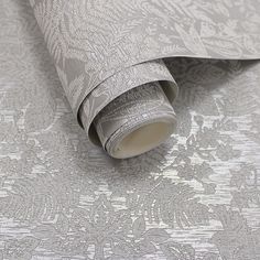 the wall paper is silver and has an intricate design on it, as well as a roll of tape