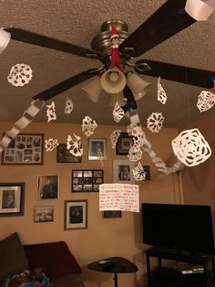 the ceiling fan is decorated with paper snowflakes