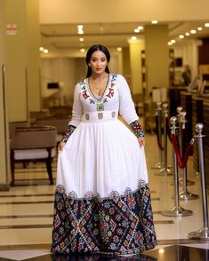 This beautiful Habesha Kemis is a stunning example of traditional Ethiopian fashion. The luxurious Menen fabric drapes elegantly over the body, creating a flattering and comfortable fit. The upper portion of the dress features a Shimena top, which is a traditional Ethiopian blouse with a loose, flowing fit. The Shimena top adds a touch of elegance and sophistication to the dress. The lower portion of the dress features a Tibeb design at the bottom, which is a type of Ethiopian embroidery that fe Ethiopian Embroidery, Ethiopian Fashion, Ethiopian Women