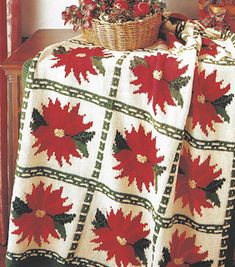 a crocheted blanket with poinsettis on it and a basket full of flowers