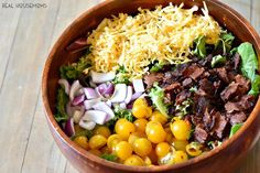 a wooden bowl filled with lots of different types of food on top of a table