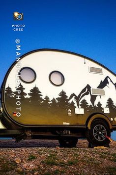 an rv parked on the side of a road with mountains and trees painted on it