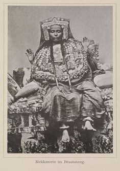 an old black and white photo of a woman sitting on a chair with her hands in the air