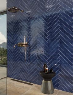 a blue tiled bathroom with a shower head and hand held shower faucet in the corner