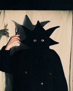 a person holding up a paper cut out of a black cat with eyes and nose