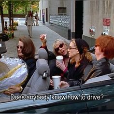 four women sitting in the back seat of a car drinking coffee and talking to each other