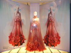 two mannequins dressed in red gowns on display