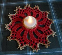 a lit candle sitting on top of a red doily