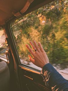 a person's hand on the dashboard of a car with trees in the background