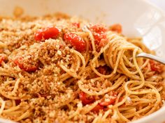 a white bowl filled with spaghetti topped with tomato sauce and parmesan crumbs