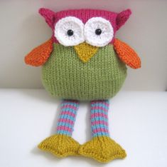 a knitted owl doll sitting on top of a white table next to a wall