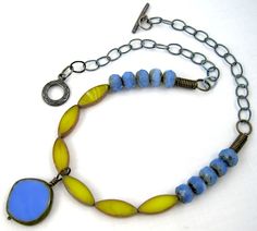 a blue and yellow beaded necklace on a chain