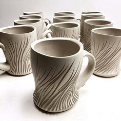 six white coffee mugs are lined up in a row on the table, one is empty